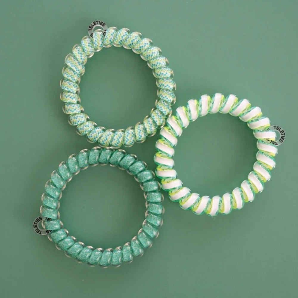 Three green beaded hair ties on a green background