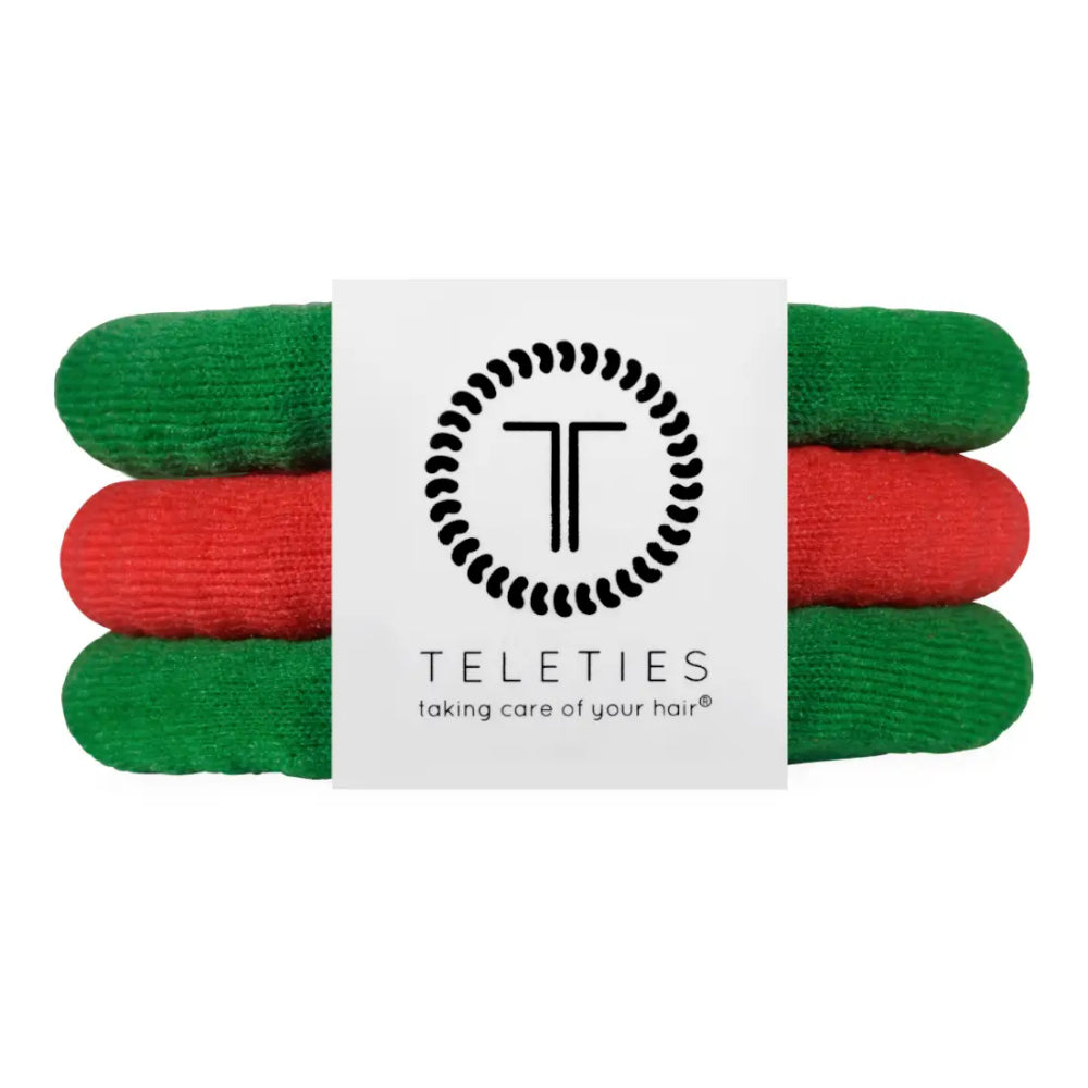 Three rolled hair ties in green and red stacked horizontally with a white paper band in the center featuring the Teleties logo and brand name.