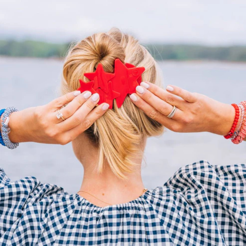 Person with red hair clips in a bun by a lake