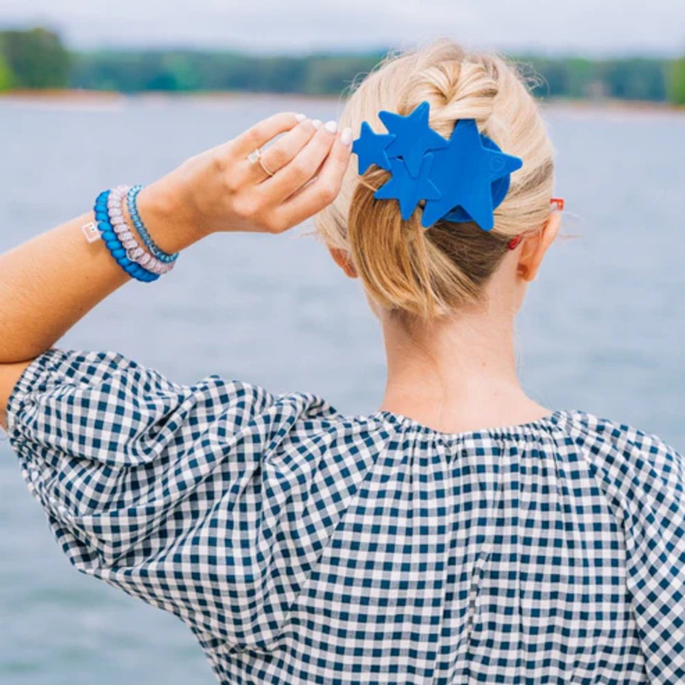Person with a blue hair clip in their hair, standing by a body of water.