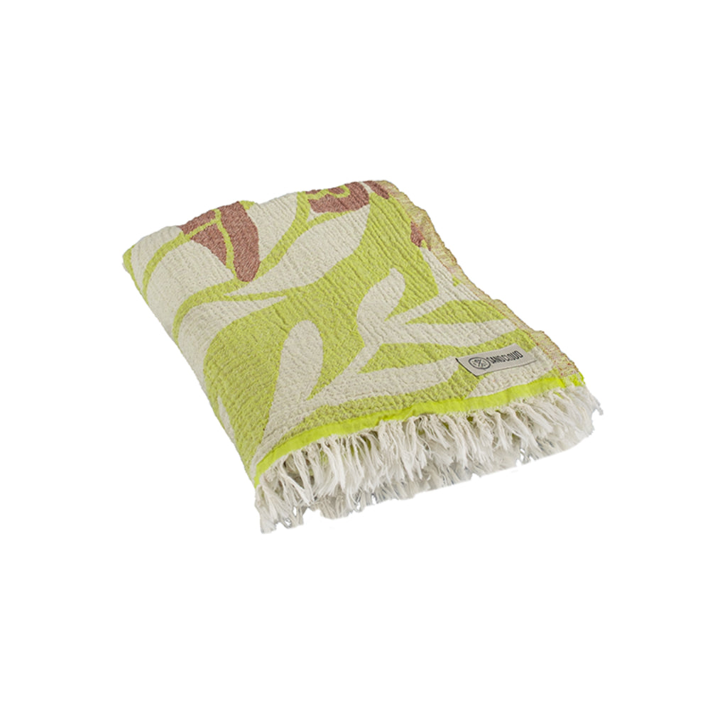 A photo of a folded beach towel with a yellow and brown sea turtle pattern and white tassel edge on a white background.