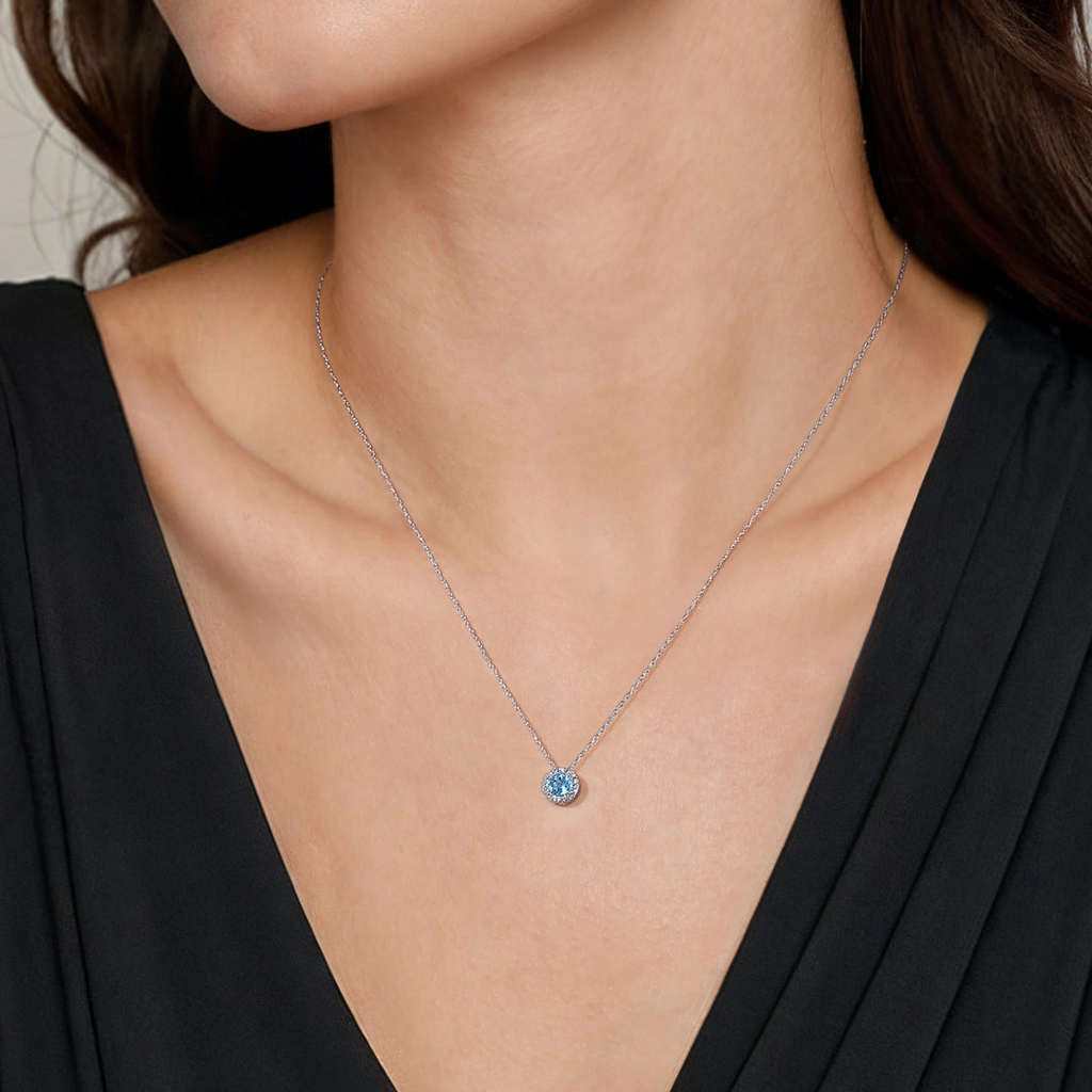 Rose gold necklace with a blue gemstone on a person wearing a black top.