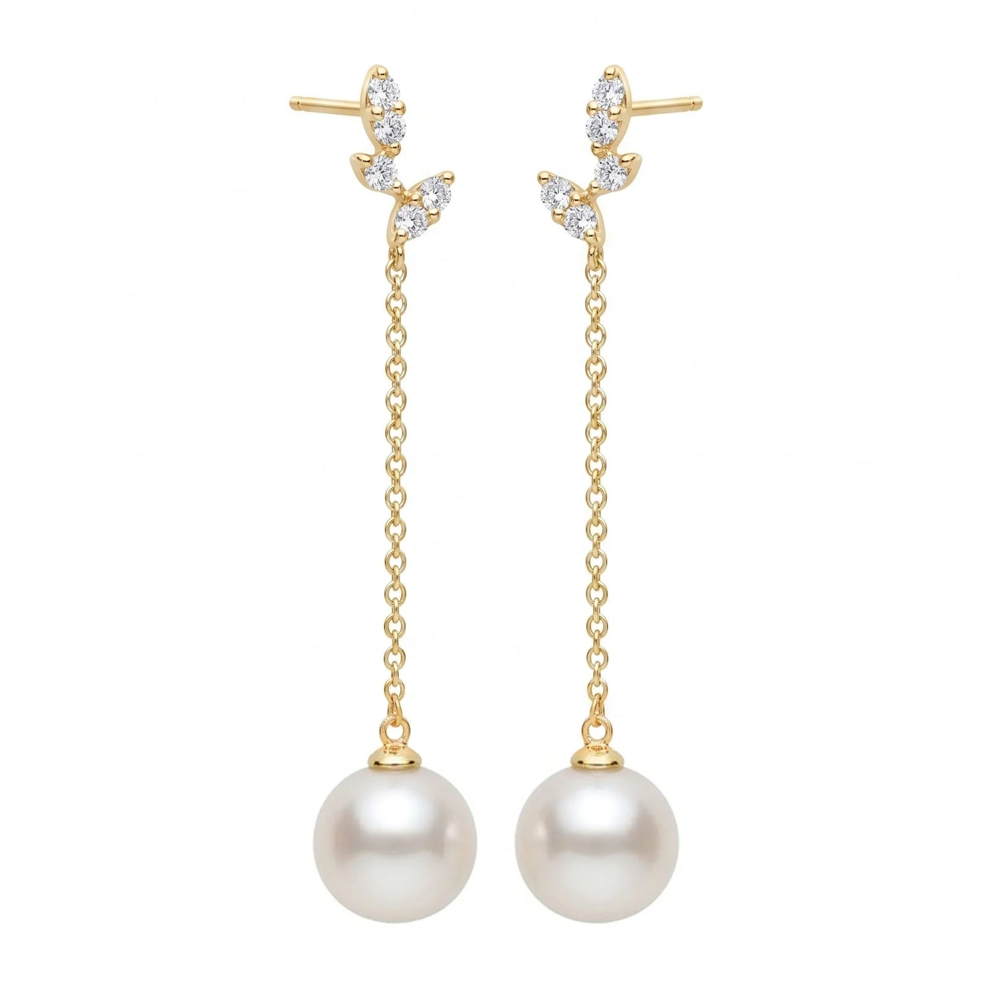 A pair of gold dangle earrings with leaf-shaped settings set with clear stones, hanging chains, and large white pearl drops, shown on a plain white background.