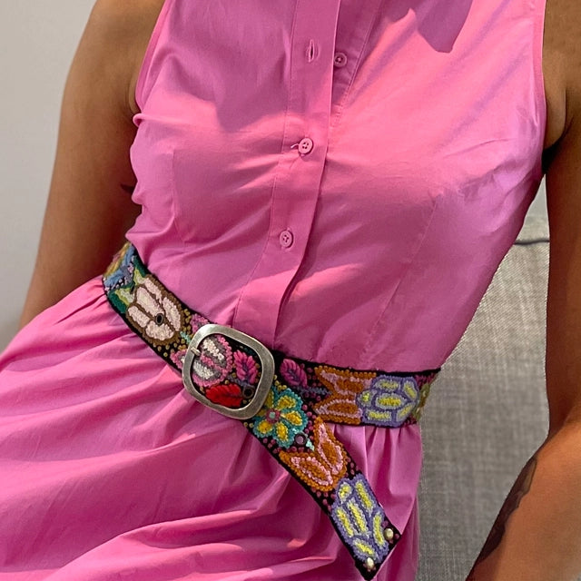 Person wearing a bright pink shirt with a colorful belt featuring floral patterns.