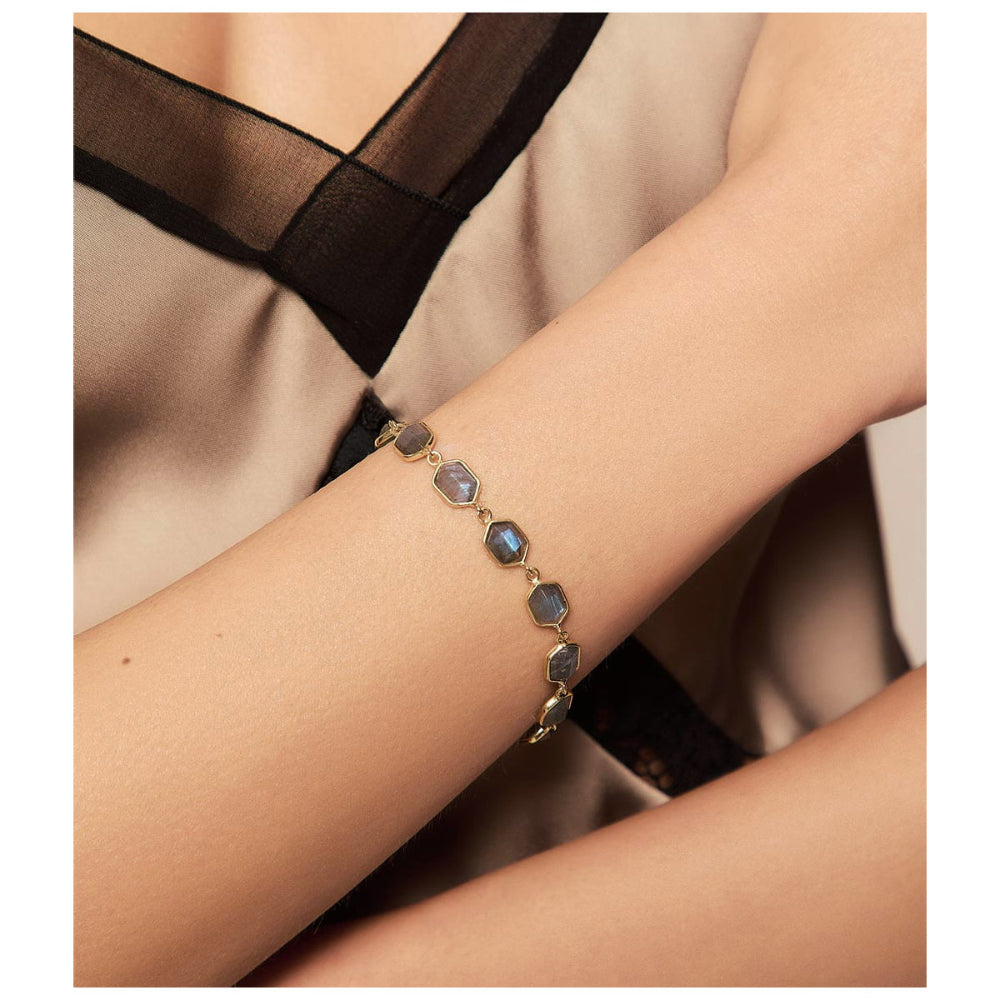A delicate gold chain bracelet with faceted gray-blue stones, shown worn on a person's wrist.