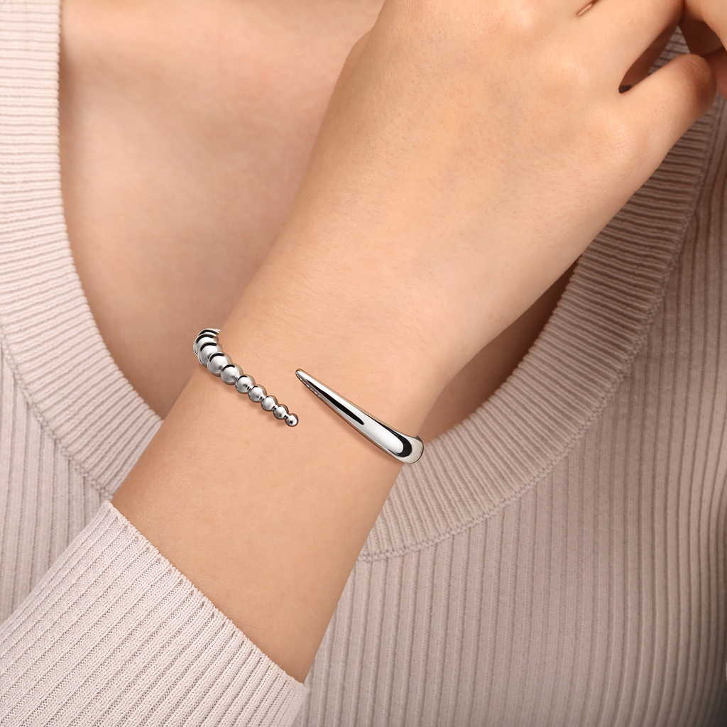 Silver bracelet on a person's wrist with a neutral background