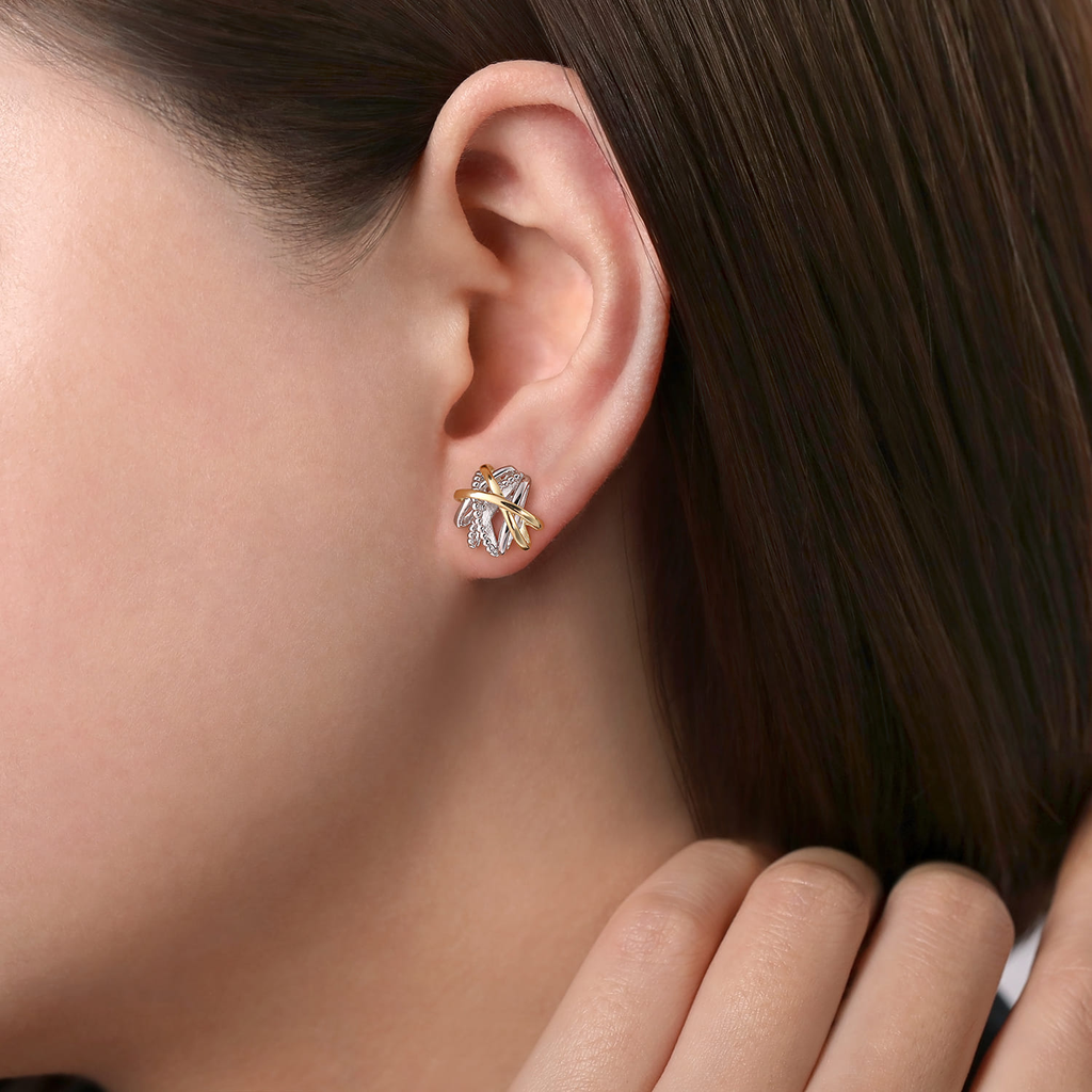 Close-up of a person wearing a gold and diamond earring.