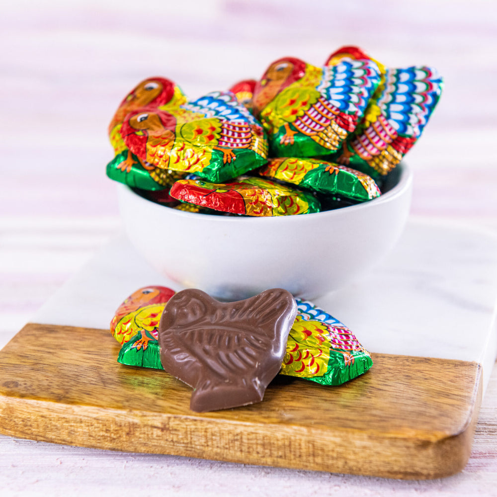 Chocolate shaped turkeys in a bowl and on a wodden surface.