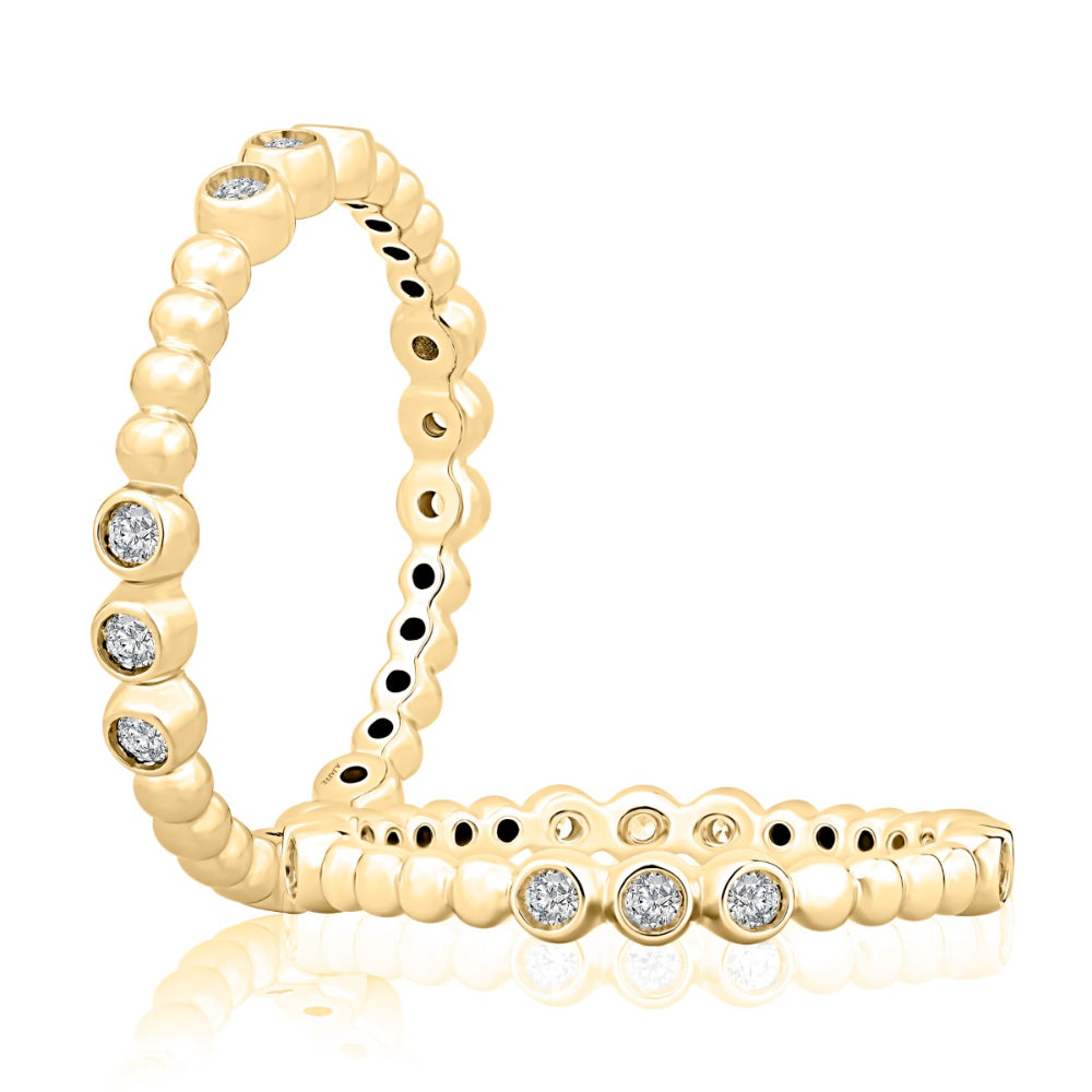 A yellow gold eternity ring featuring round-cut clear gemstones set along the band, displayed on a clean white background with a soft reflection.