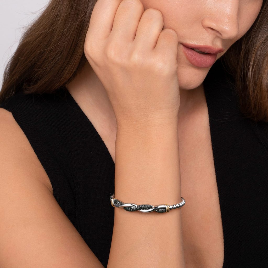 Close-up of a woman's wrist wearing a silver bracelet against a neutral background