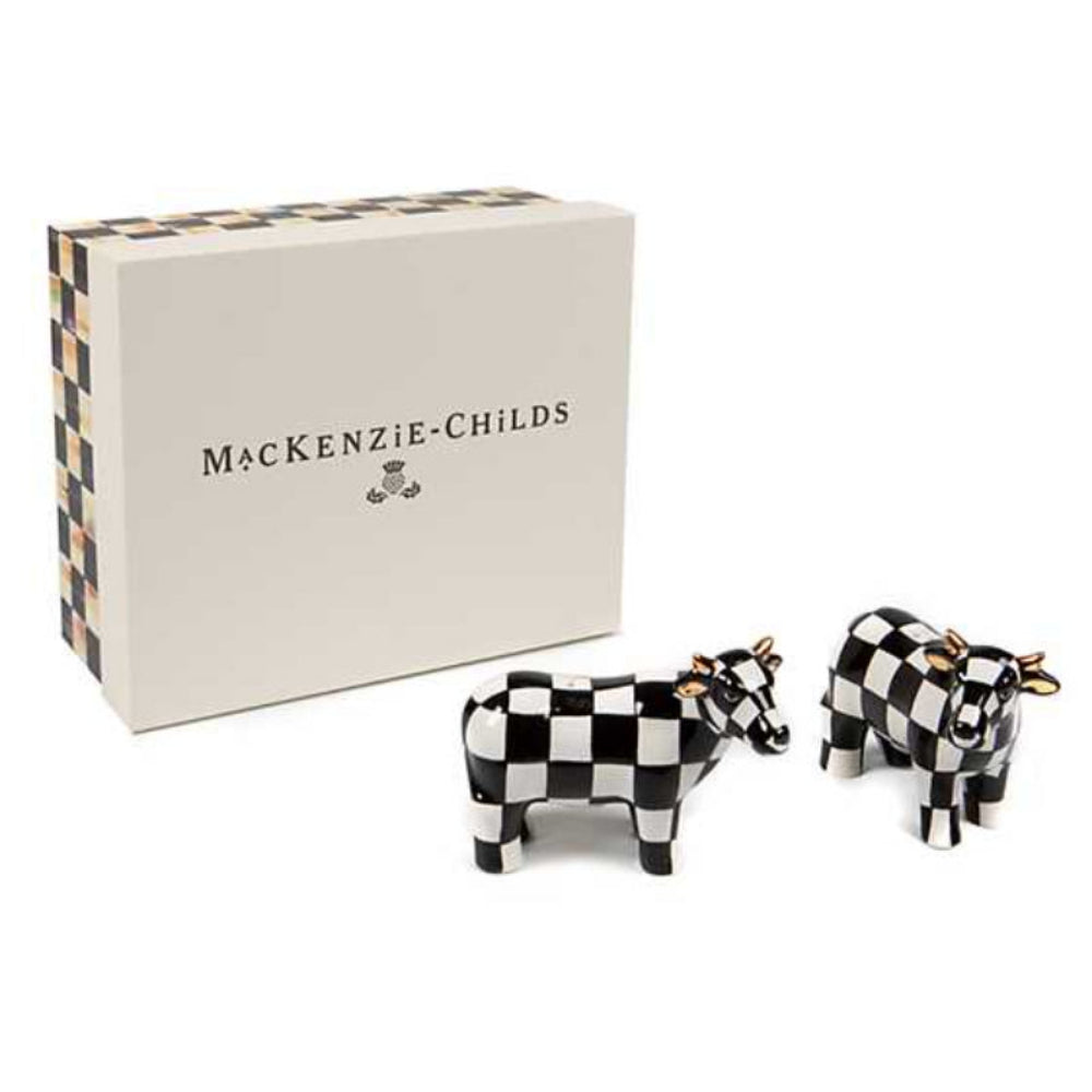 A pair of hand-painted ceramic cows with in a black checkered pattern and gold luster ears designed to hold salt and pepper with box on a white backround