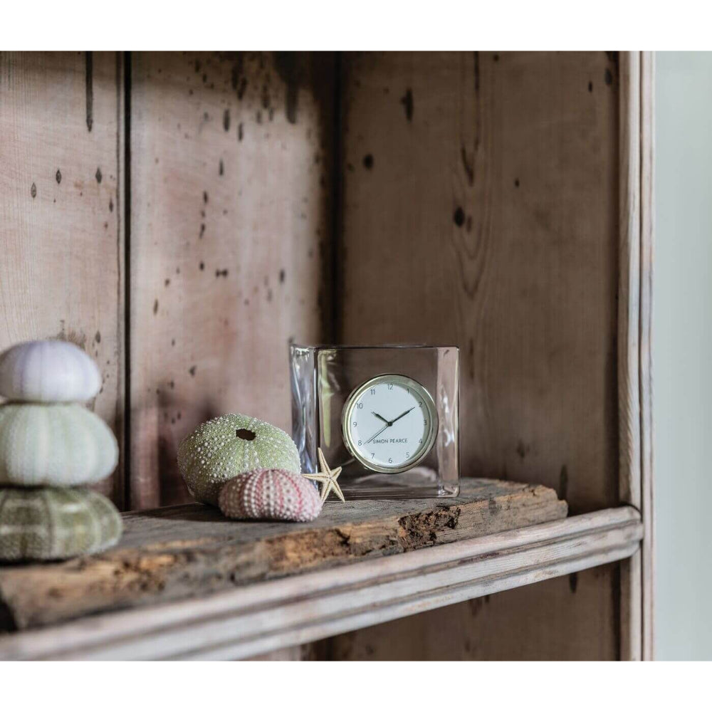 Life style photo of the Simon Pearce Woodbury Clock on a wood shelf with sea shells and a small starfish.