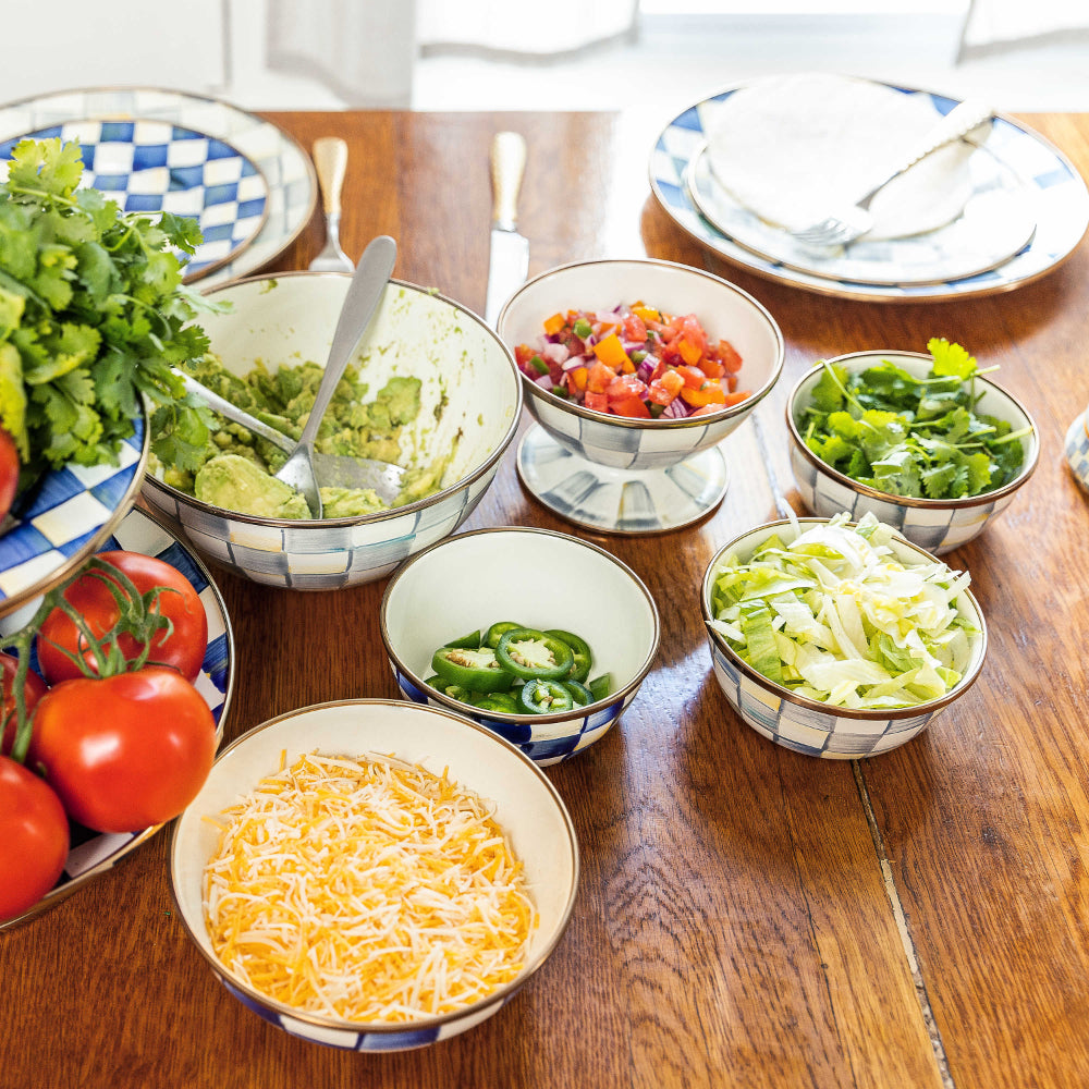 Life style photo of MacKenzie-Childs Sterling Check Enamel Everyday Medium Bowl on table with other bowel and serveware item