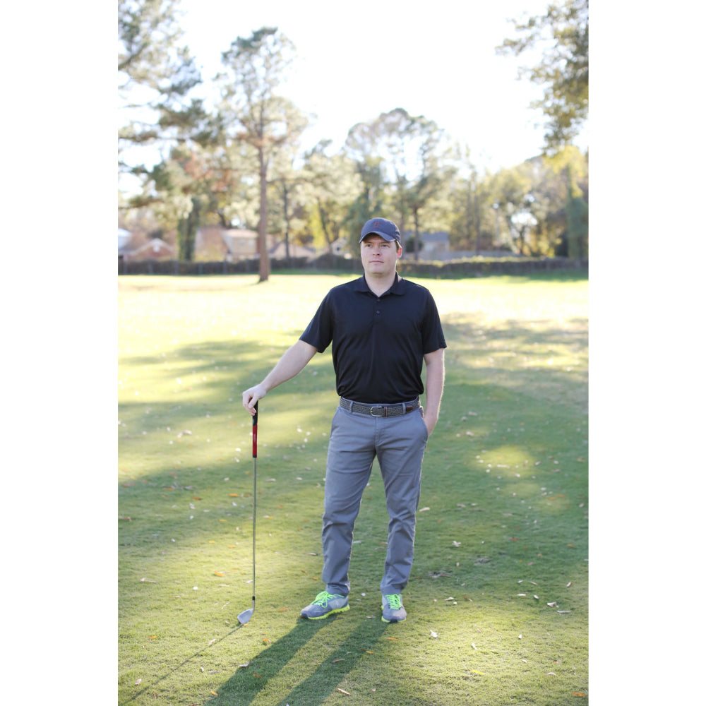 Person wearing woven belt in outdoors with black shirt on on golf course.