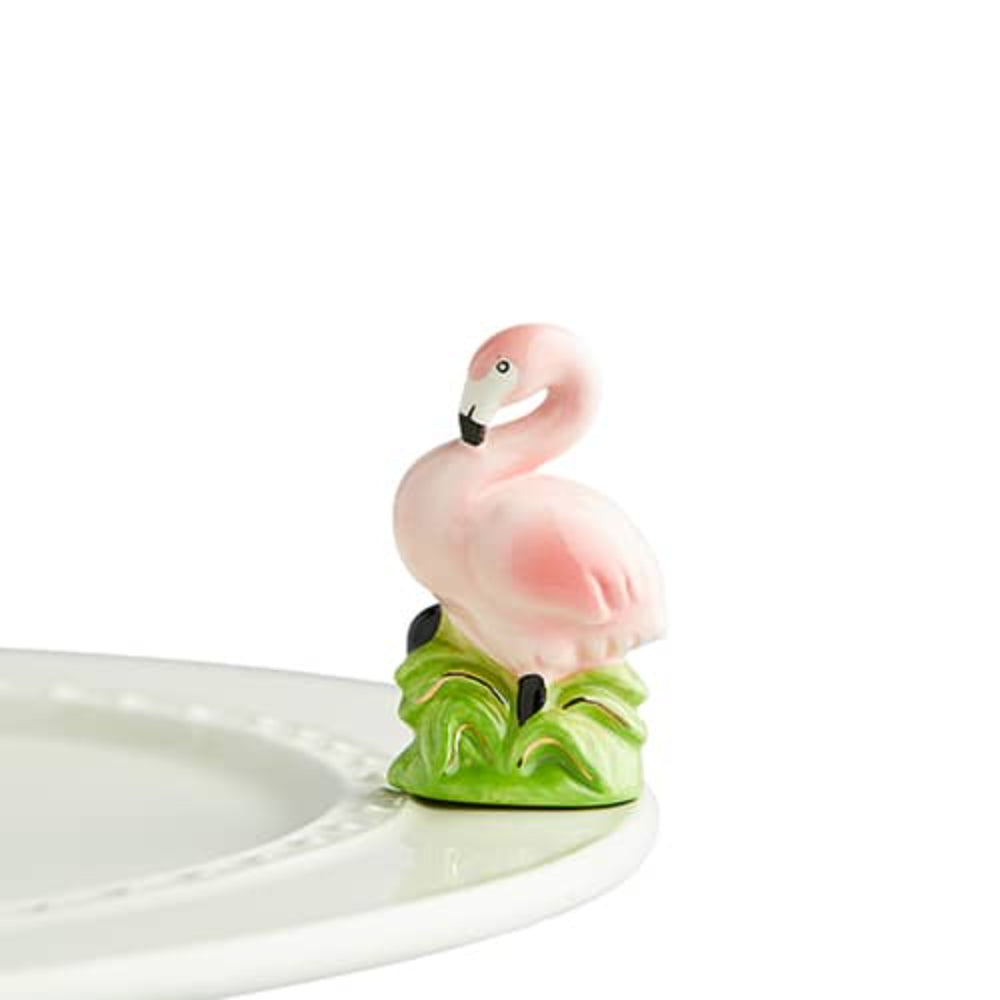 A small ceramic figurine of a pink flamingo standing on green leaves, designed as a kitchen or room accent.