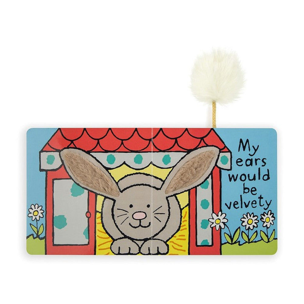 The opened book "If I Were a Bunny" opened page with bunny coming out of a red house with grass and flowers around it with a blue sky with black text 'My ears would be velvety' with white tail on a white backround.