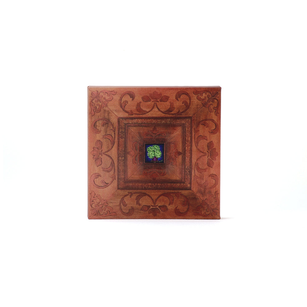 Decorative wooden panel with intricate carvings and green tree against a blue backround, on a white background.