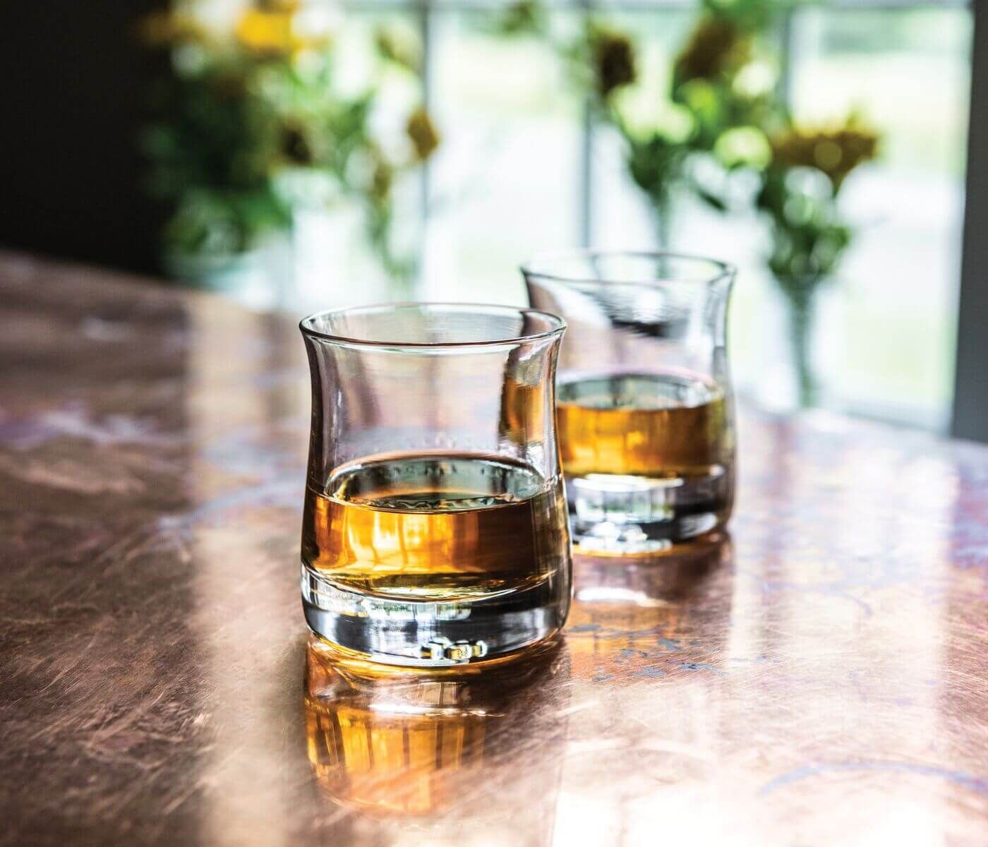 A set of whiskey glasses with whiskey inside of them on a table display.