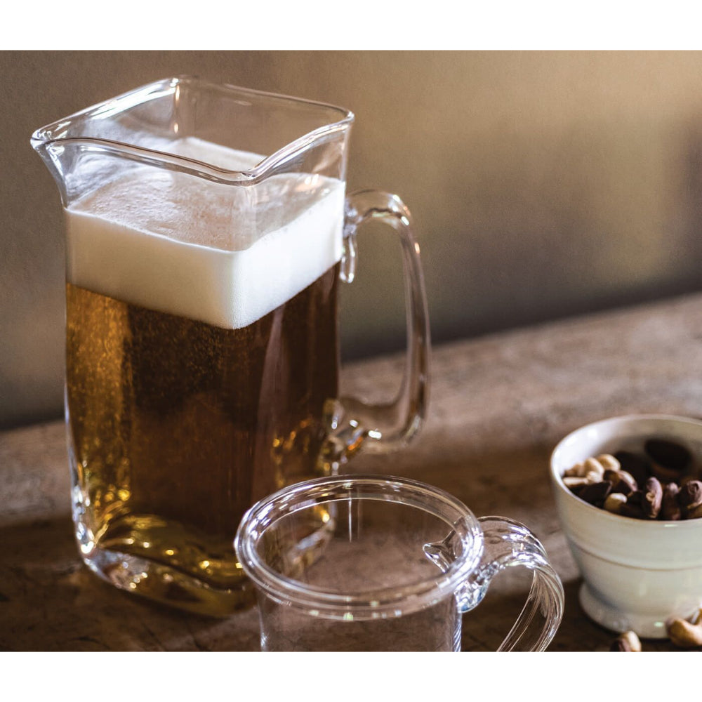 Glass pitcher filled with a beverage with other decor items on display.