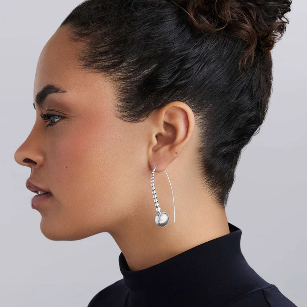 Side profile of a woman wearing a silver earring with graduated beads