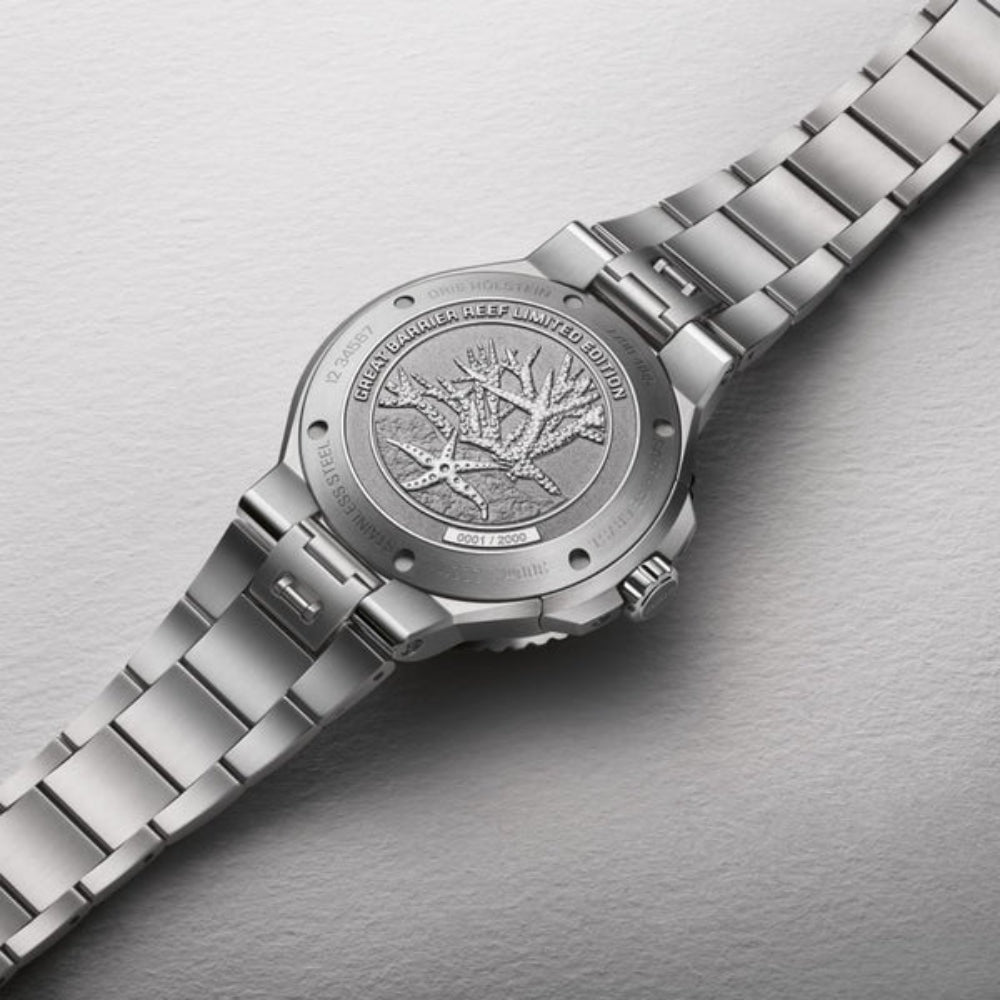 Close-up of a silver watch with detailed engraving on a gray background
