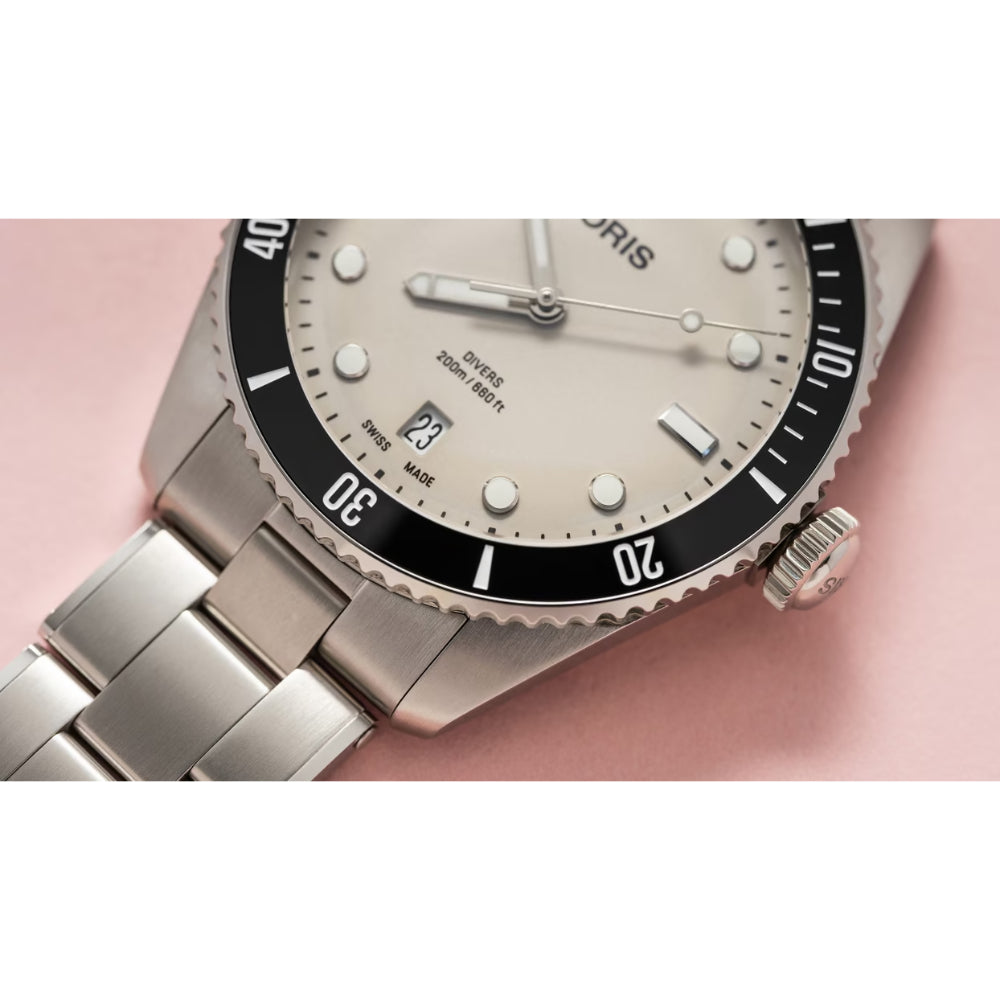 Silver watch with a detailed face on a pink background