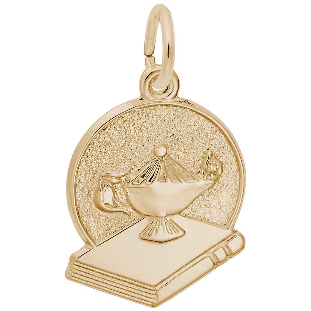 Gold charm of a genie lamp on a book with glittery texture.