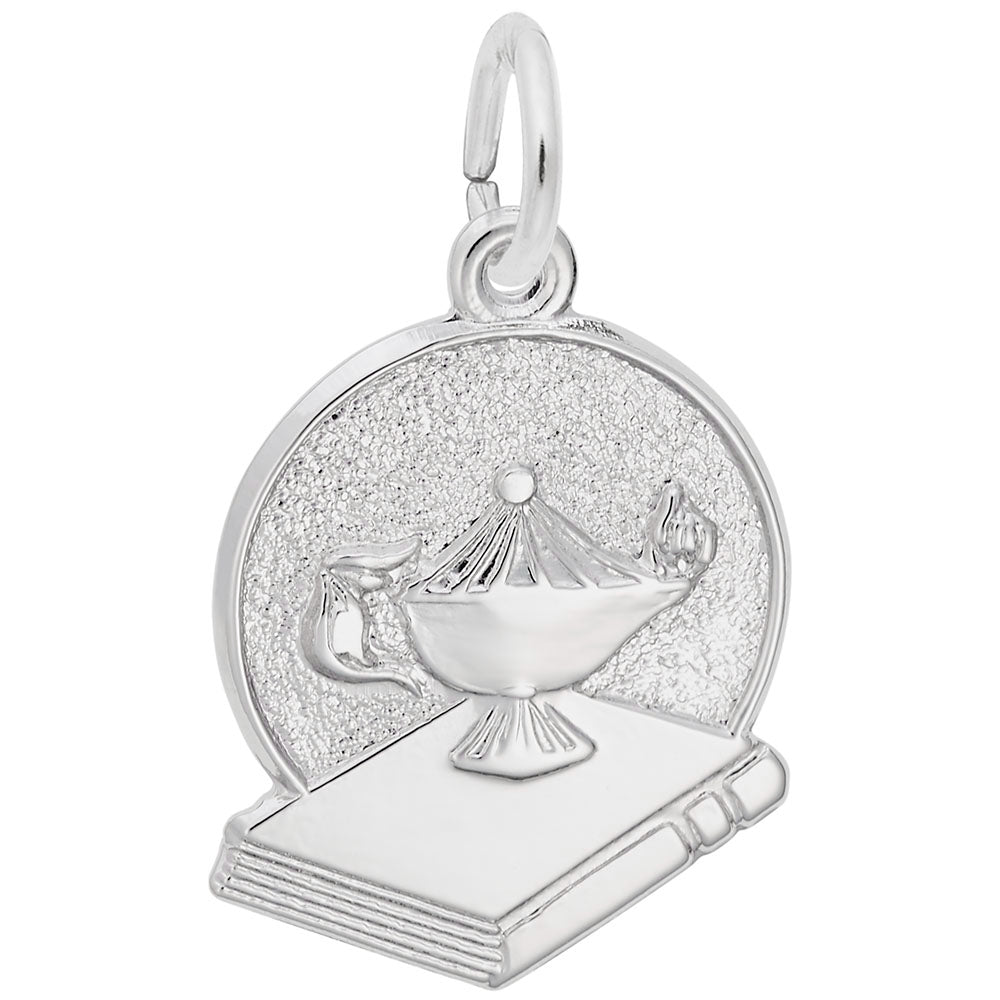 Silver charm of a genie lamp on a book with glittery texture.