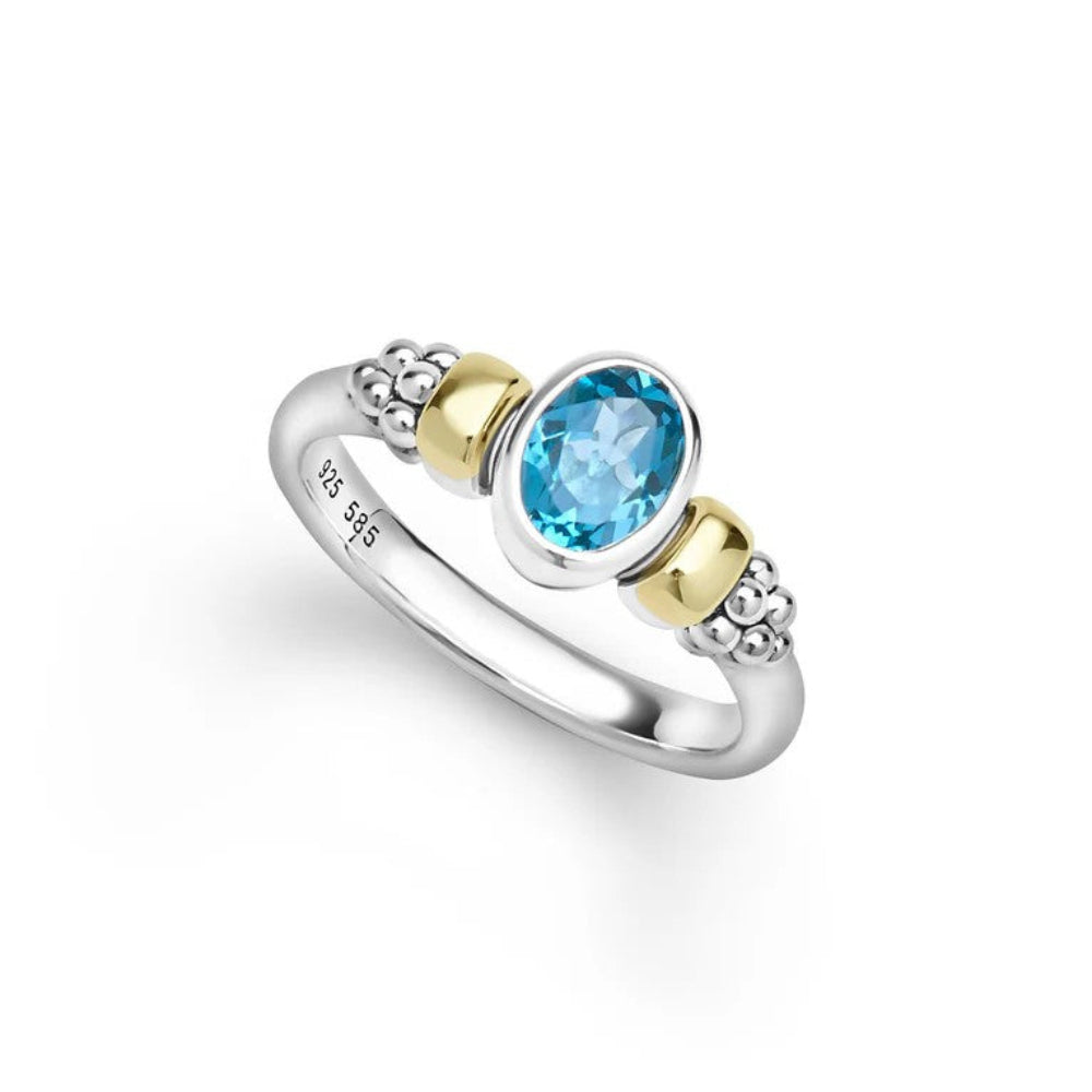 A sterling silver and yellow gold ring featuring an oval-cut light blue topaz center stone, with textured silver bead details on either side of the band. 