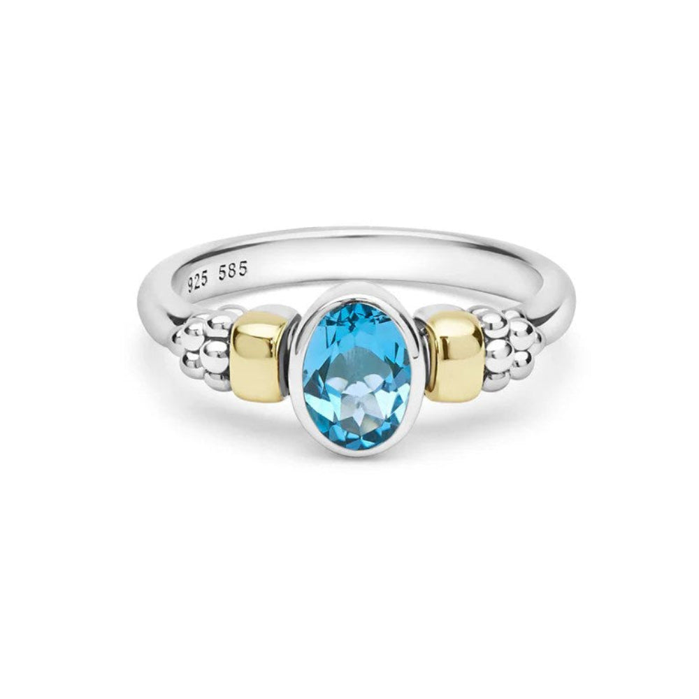 A sterling silver and yellow gold ring featuring an oval-cut light blue topaz center stone, with textured silver bead details on either side of the band. 
