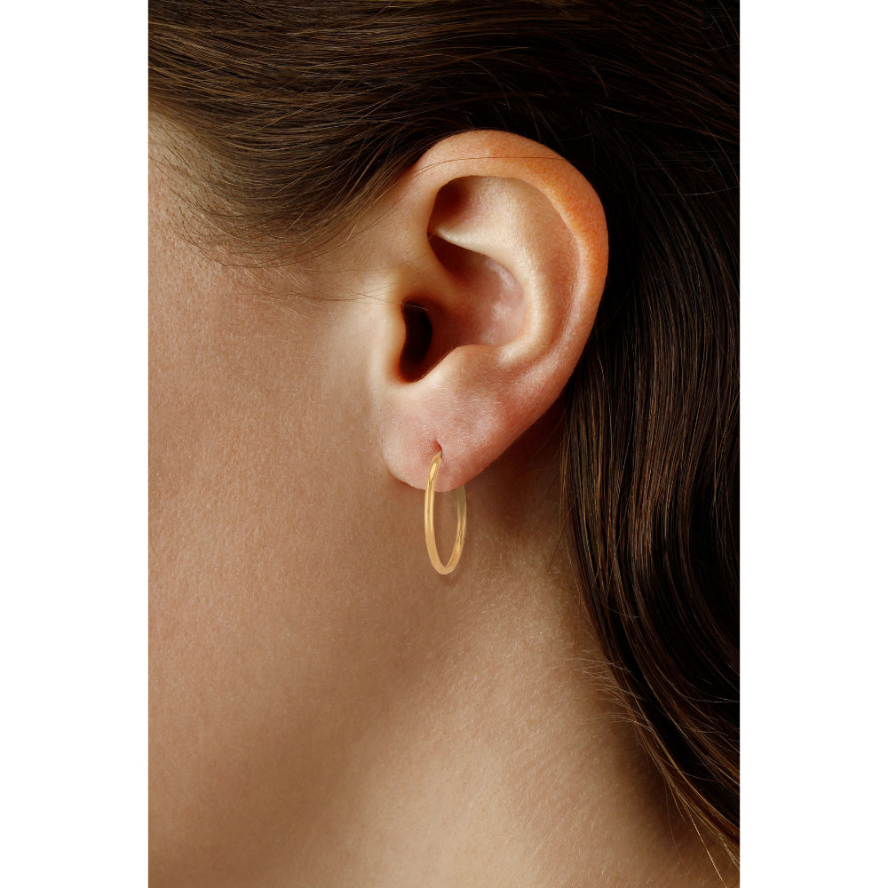 Gold hoop earring worn by a person with brown hair.