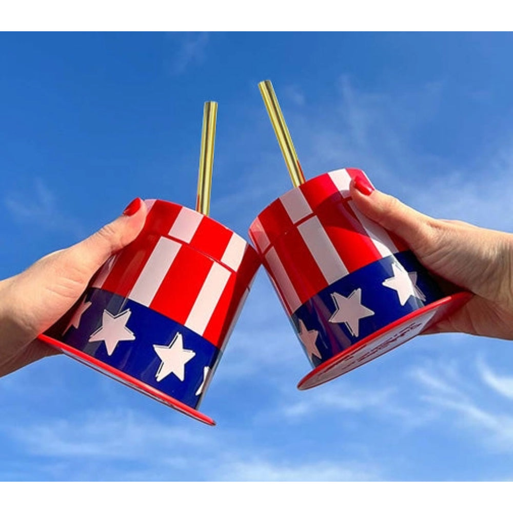 2 people sharing cheers with USA sipper cups with gold straws in outdoor setting. 