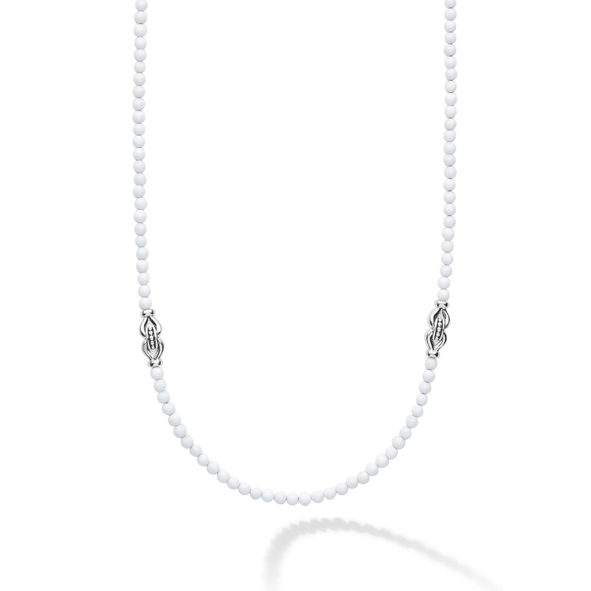A delicate white beaded necklace with ornate silver-toned Celtic knot clasp ends, displayed on a clean white background with a soft reflection below.