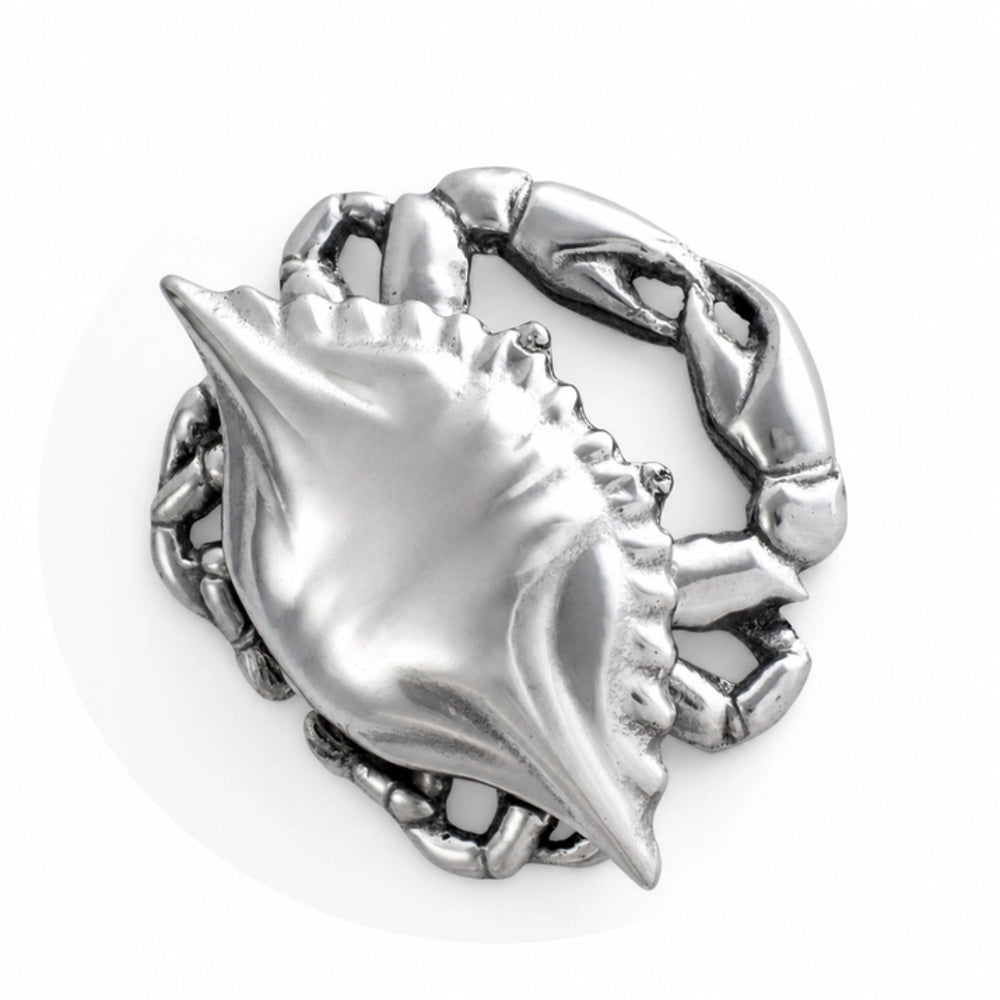 A silver-toned metal ring shaped like a crab with a conch shell and chain details, shown on a plain white background.