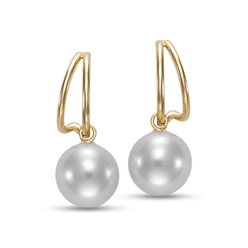 A pair of gold huggie hoop earrings with large, lustrous white freshwater pearls hanging from the loops, shown against a plain white background.
