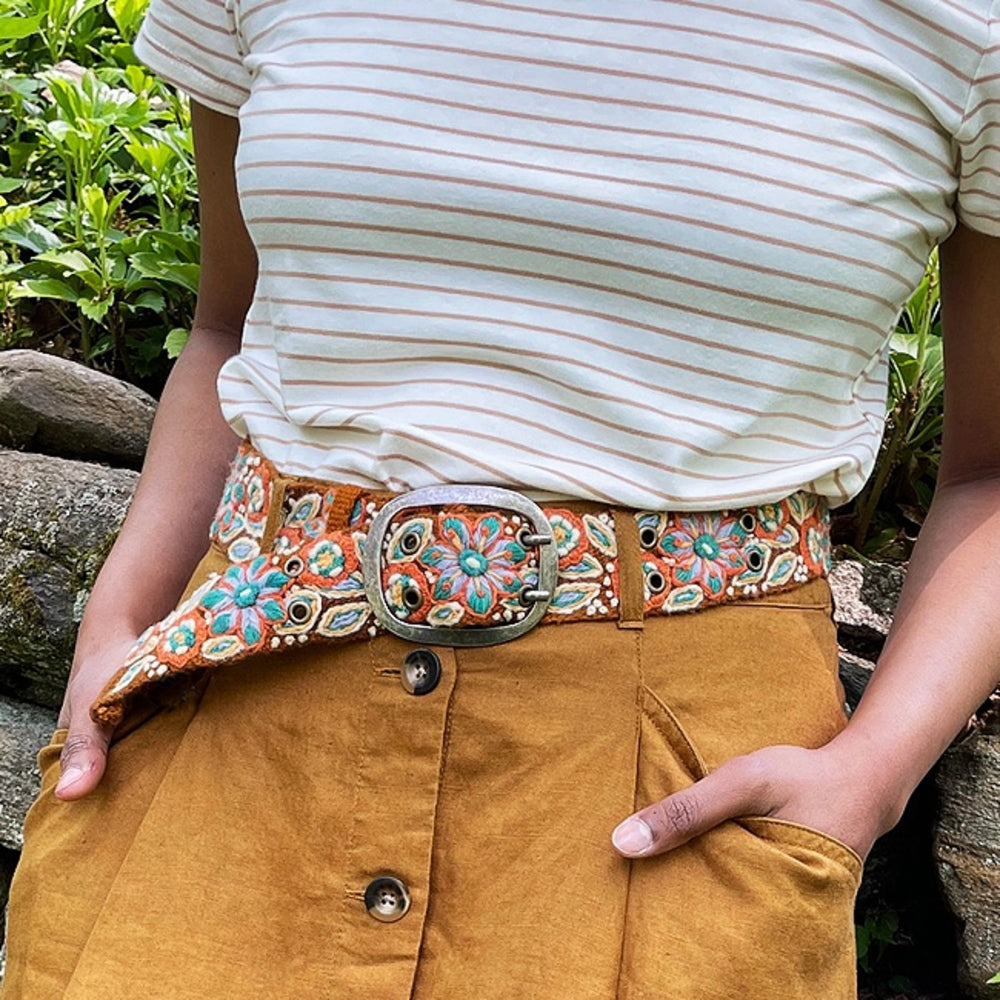 Person wearing a decorative belt with floral patterns in an outdoor setting