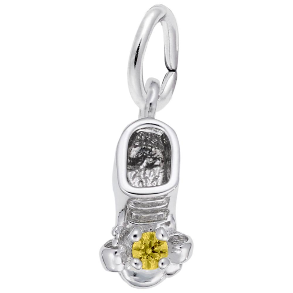 Silver baby-bootie charm with a yellow gemstone on a white background