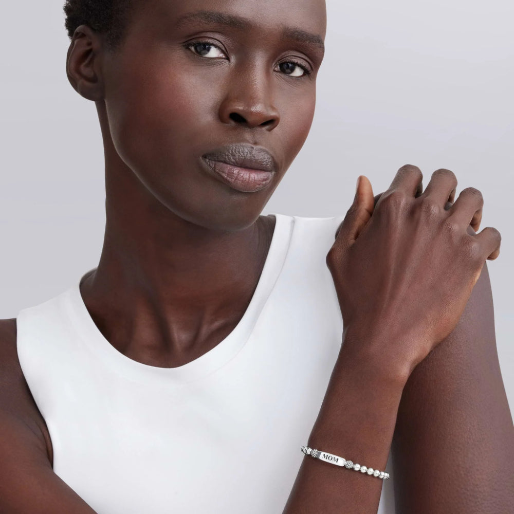 Woman wearing a white sleeveless top with a silver bracelet on a plain background