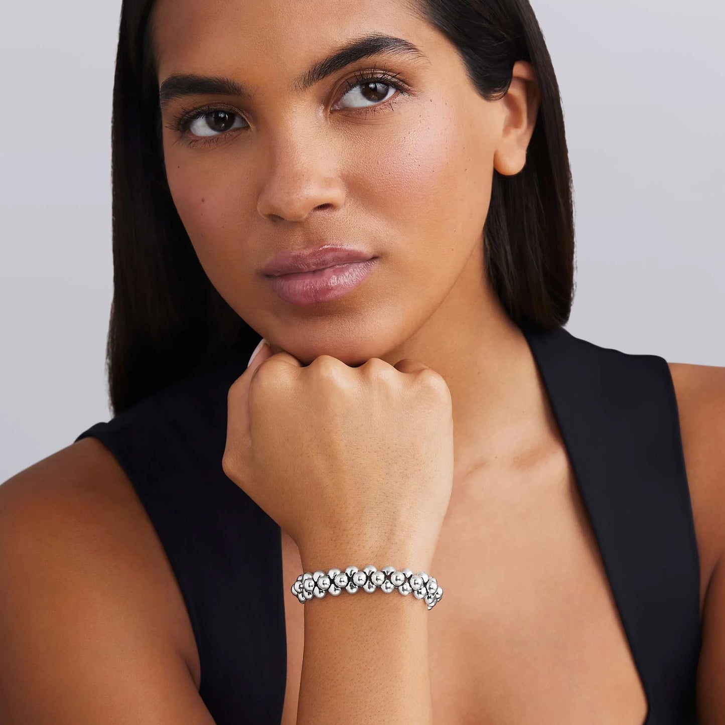 Woman wearing a silver bracelet on a plain background