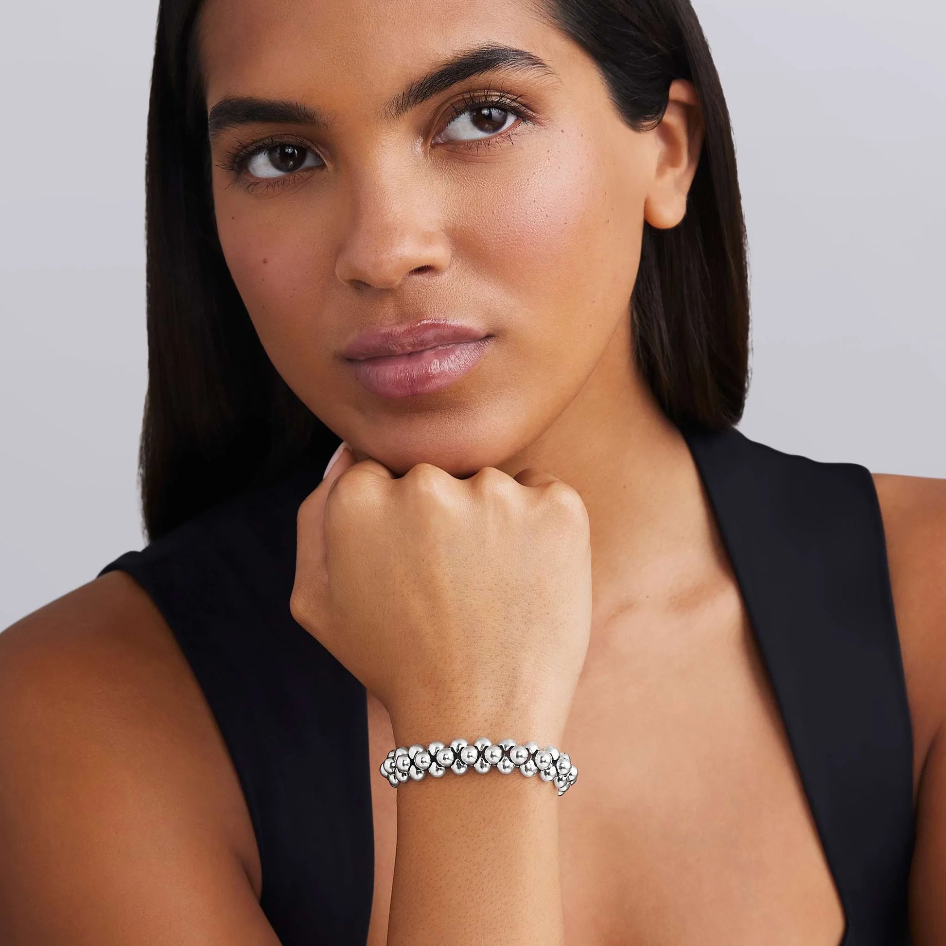 Woman wearing a silver bracelet on a plain background