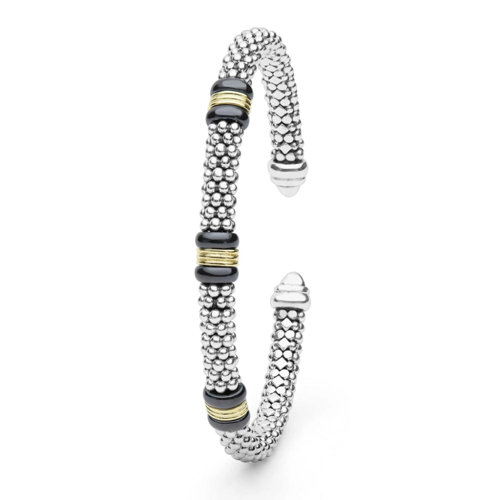 A silver-toned beaded cuff bracelet with three black disc accents and two gold spacer rings, shown on a clean white background.