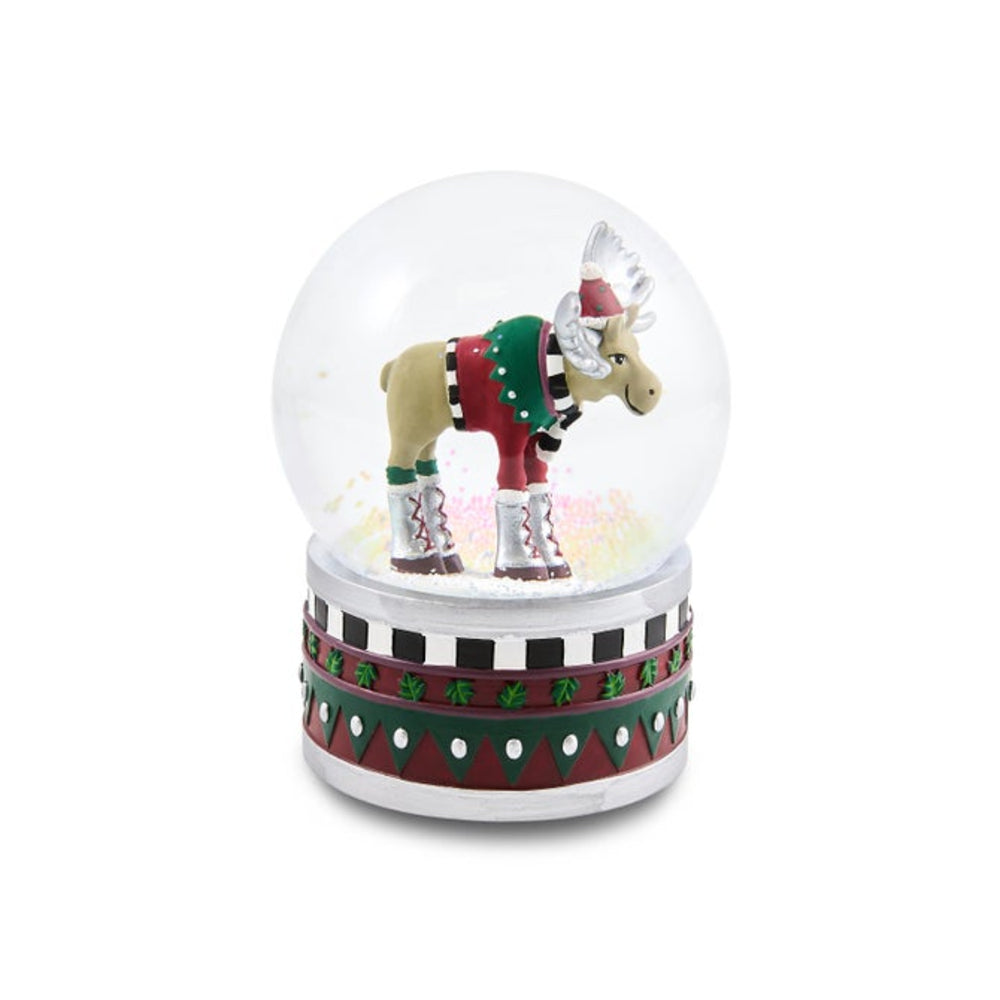 A festive moose snow globe decoration featuring a tan moose wearing a red and green sweater and boots inside a clear glass globe, set on a patterned red, green, and white base against a white background.