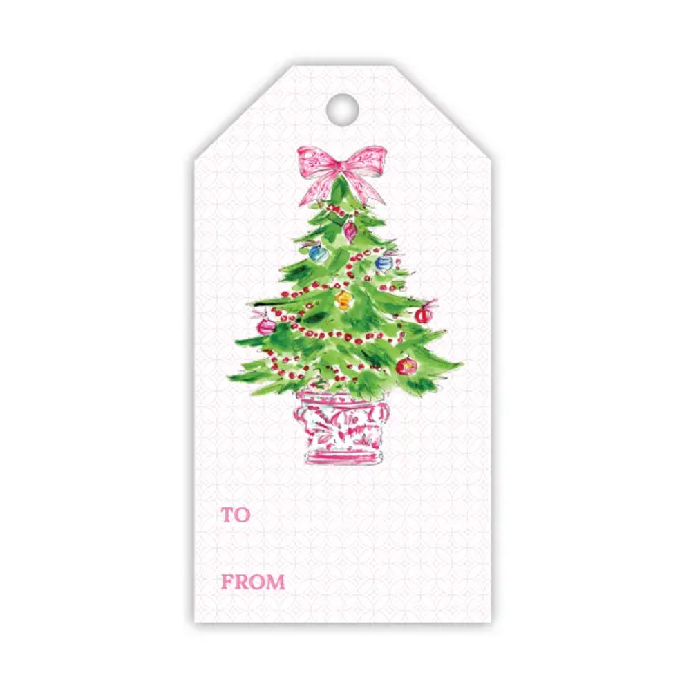 A white gift tag with a watercolor illustration of a decorated Christmas tree in a pink pot, featuring a pink bow on the tree and the text 'TO' and 'FROM' in pink at the bottom.