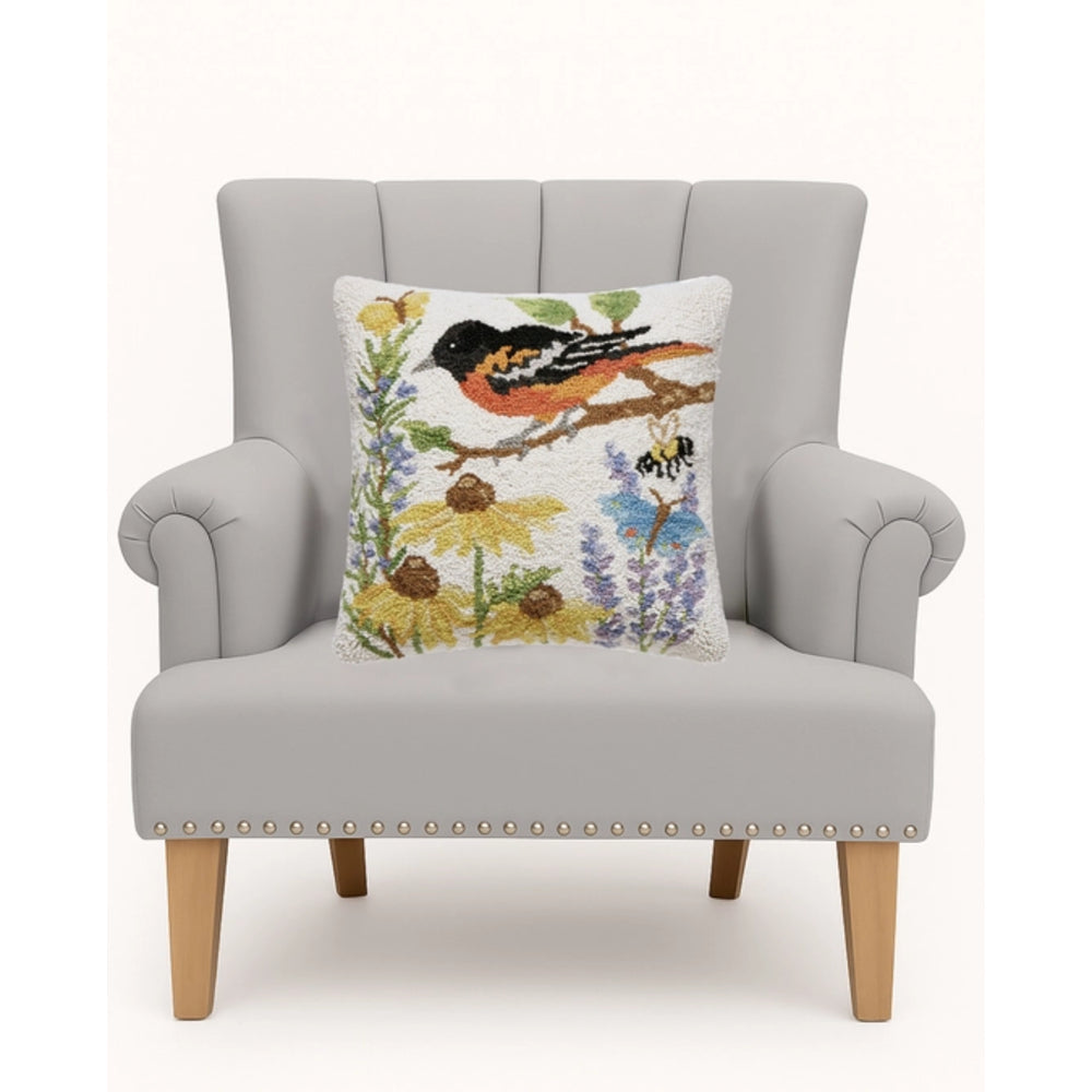 Gray armchair with a decorative pillow featuring birds and flowers on a white background.