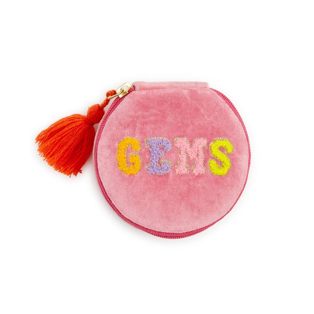 A round pink velvet coin purse with a tassel zipper pull, featuring the word 'GEMS' embroidered in colorful glitter letters across the front.