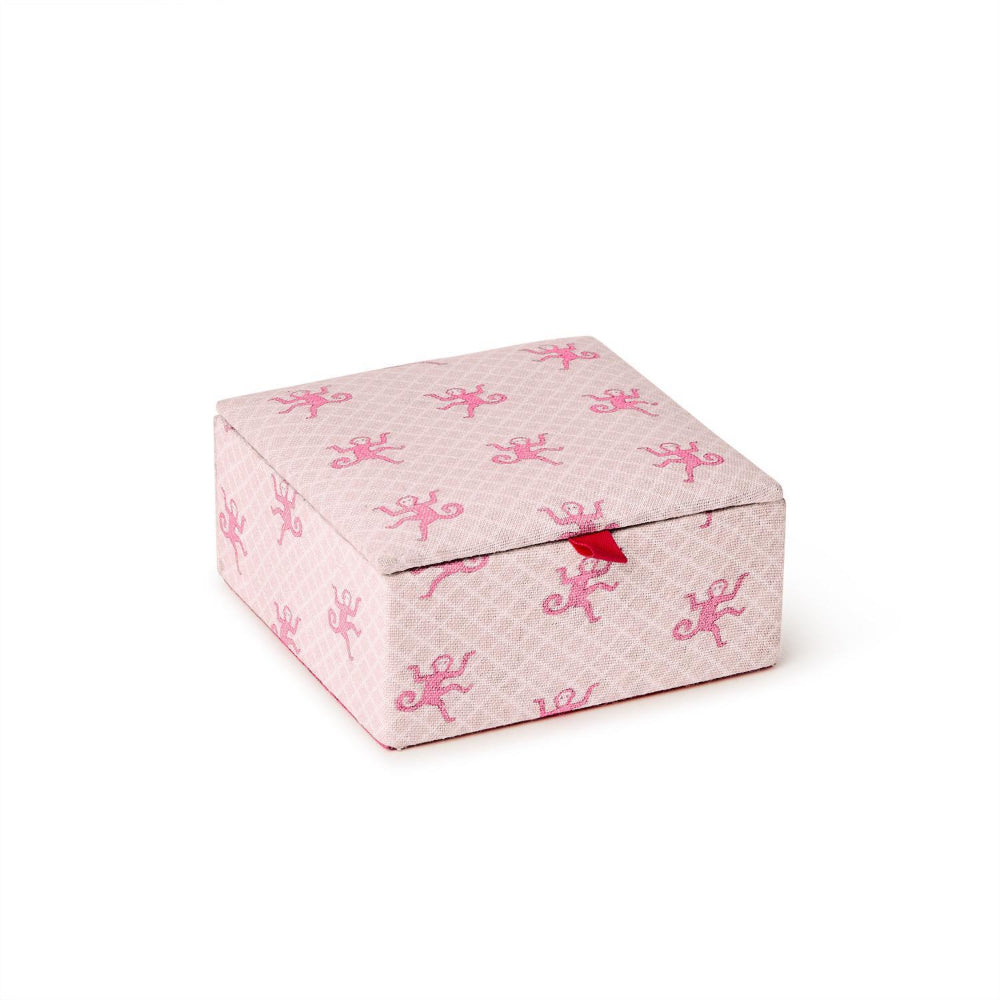A small square gift box with a hinged lid, covered in light pink patterned paper with darker pink cherub motifs and a small red ribbon tied at the front, shown on a white background.