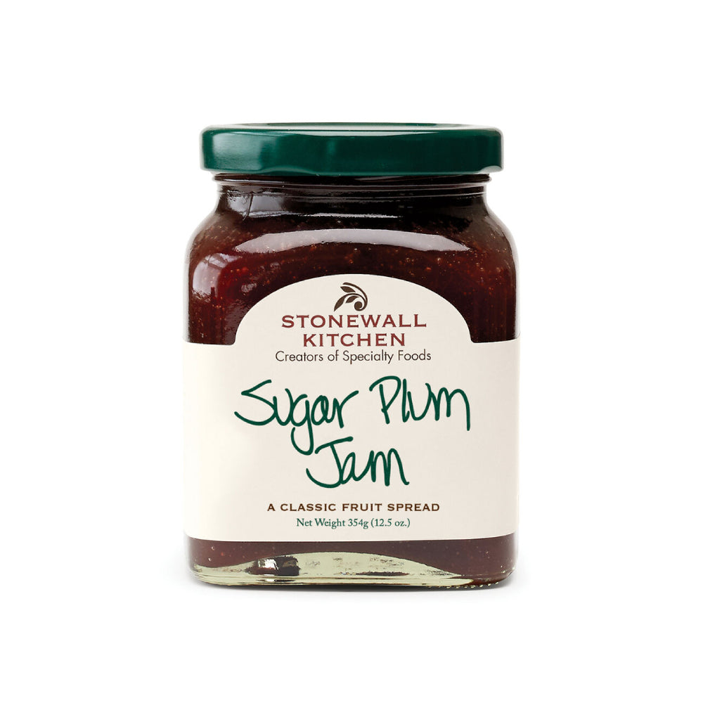 A glass jar of Stonewall Kitchen Sugar Plum Jam with a dark green lid and an off-white label, set against a plain white background.
