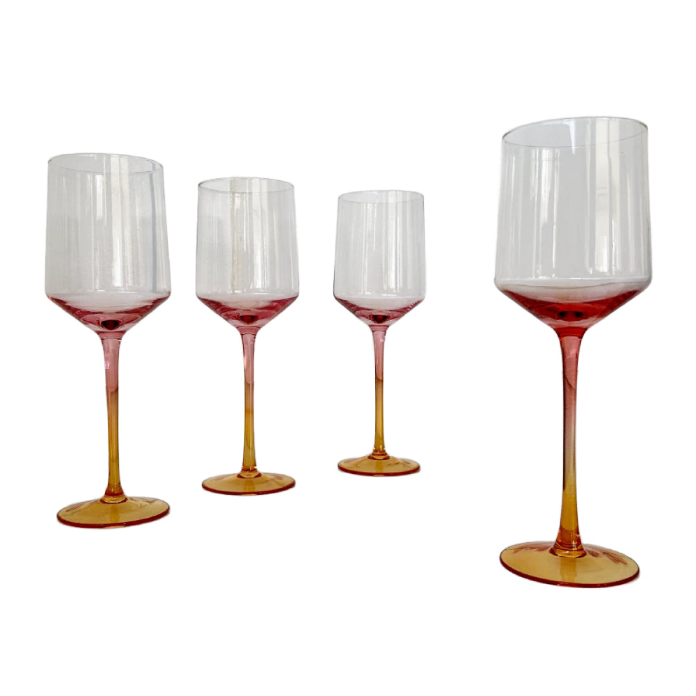 Four clear wine glasses with a translucent amber-orange base, arranged against a plain white background.