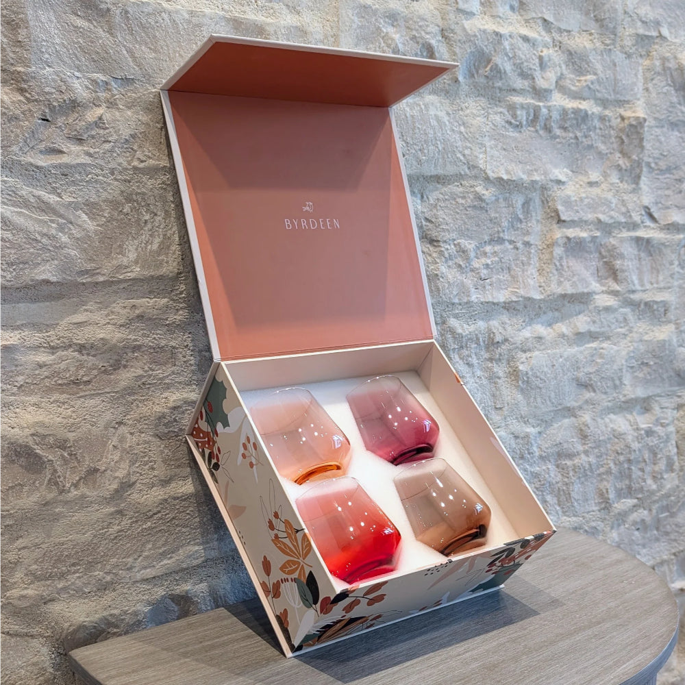 Set of four glass tumblers in a decorative box with 'Borocen' branding against a stone wall.
