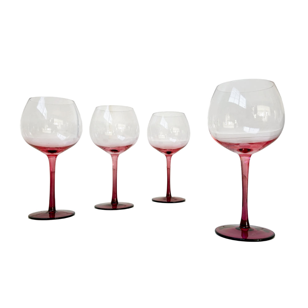 Four clear wine glasses with deep pinkish-red stems and bases, arranged in descending size order against a plain white background.